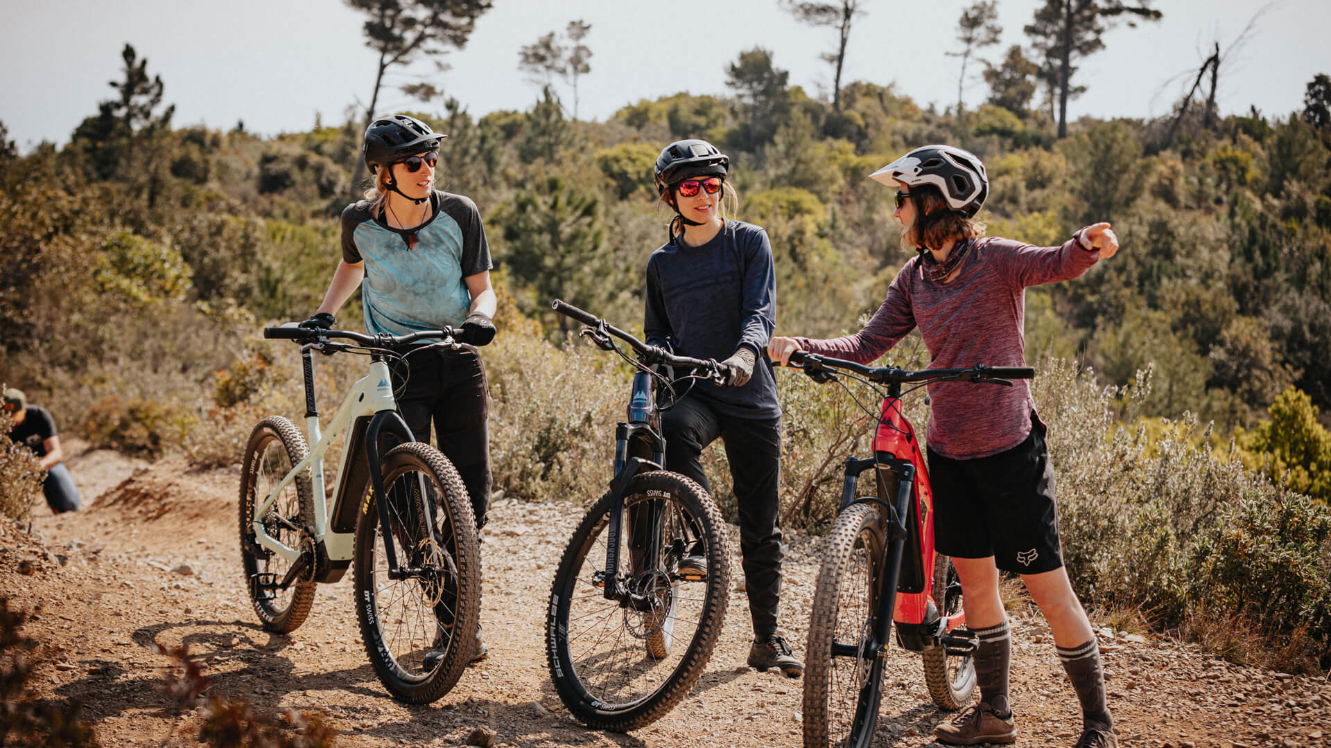 Drei Mountainbikerinnnen mit E-MTBs rasten während einer Tour