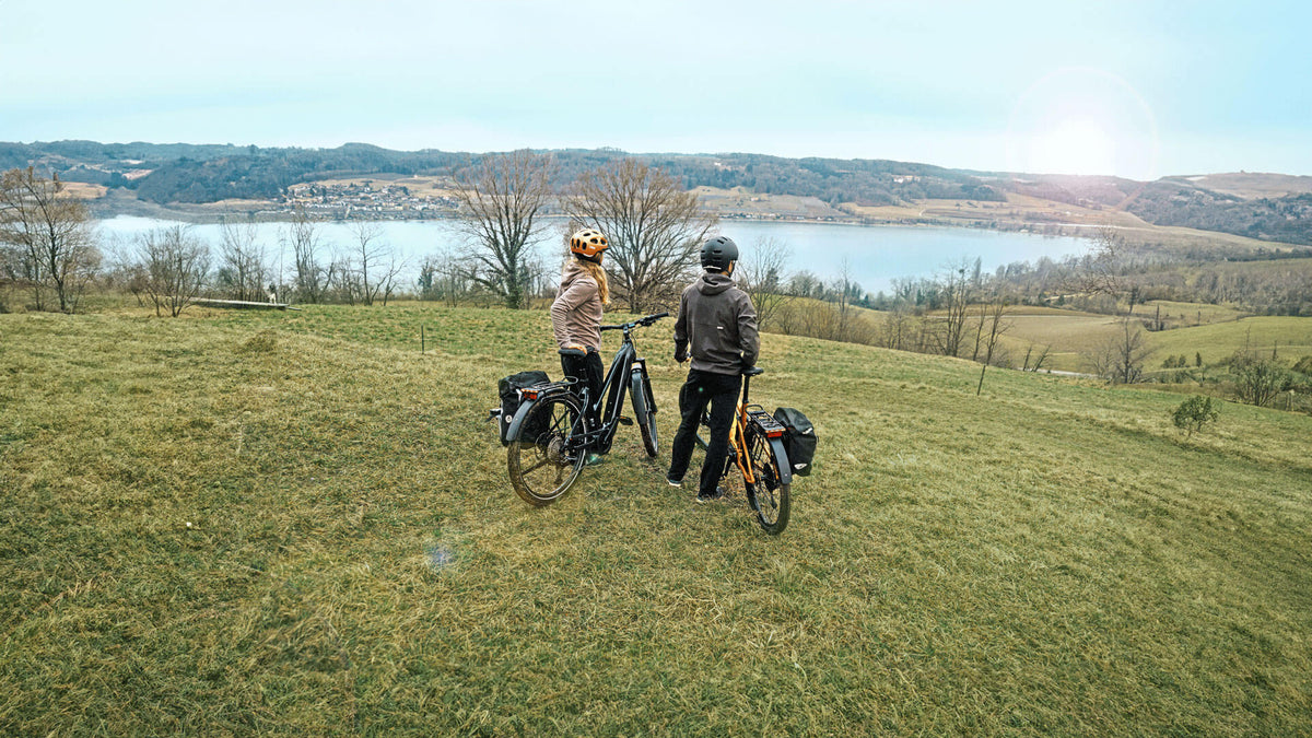 Pärchen mit Trekking-Bikes überblicken Landschaft mit See im Tal