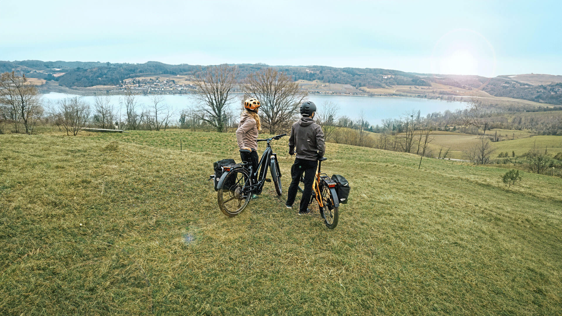 Pärchen mit Trekking-Bikes überblicken Landschaft mit See im Tal