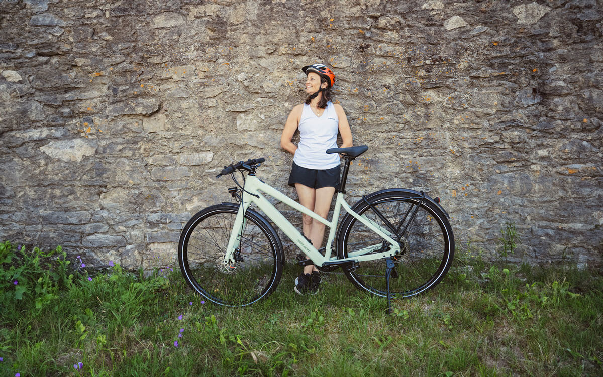 Bikerin mit LUMO Tereno lehnt sich in einer Pause an eine Steinwand