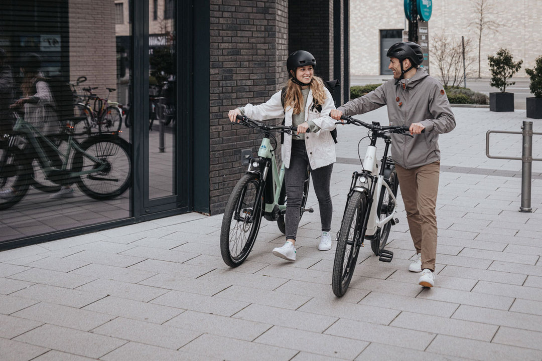 Zwei Personen (Mann/Frau) schieben ihre eBikes in der Fußgängerzone